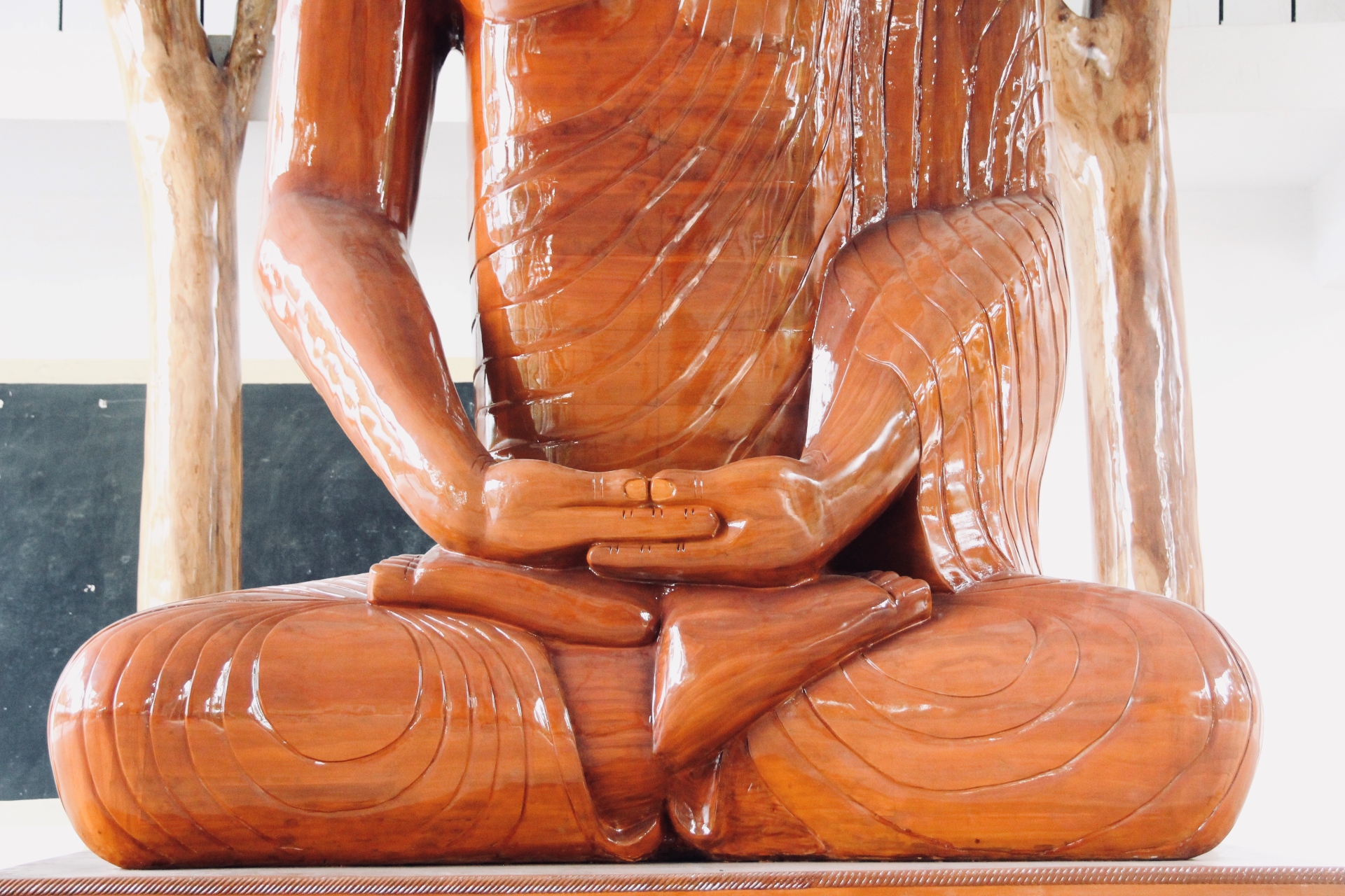 Close-up of a carved wooden deity sculpture's torso and shoulder ornamentation