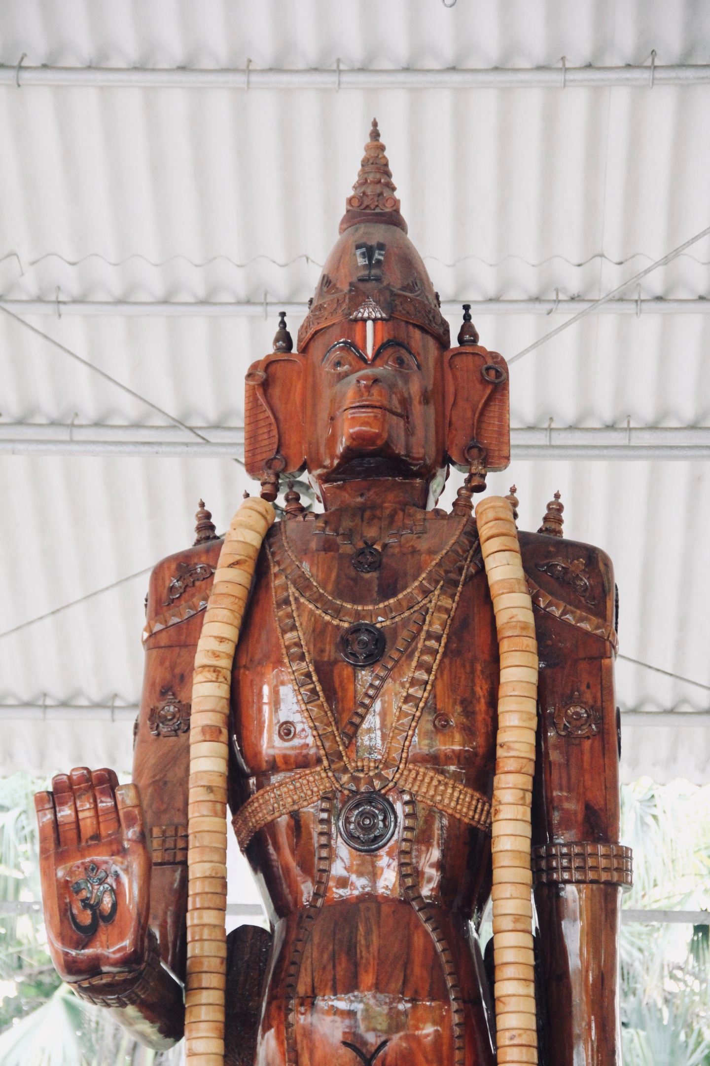 Close-up of a carved wooden deity sculpture's crowned head and shoulders