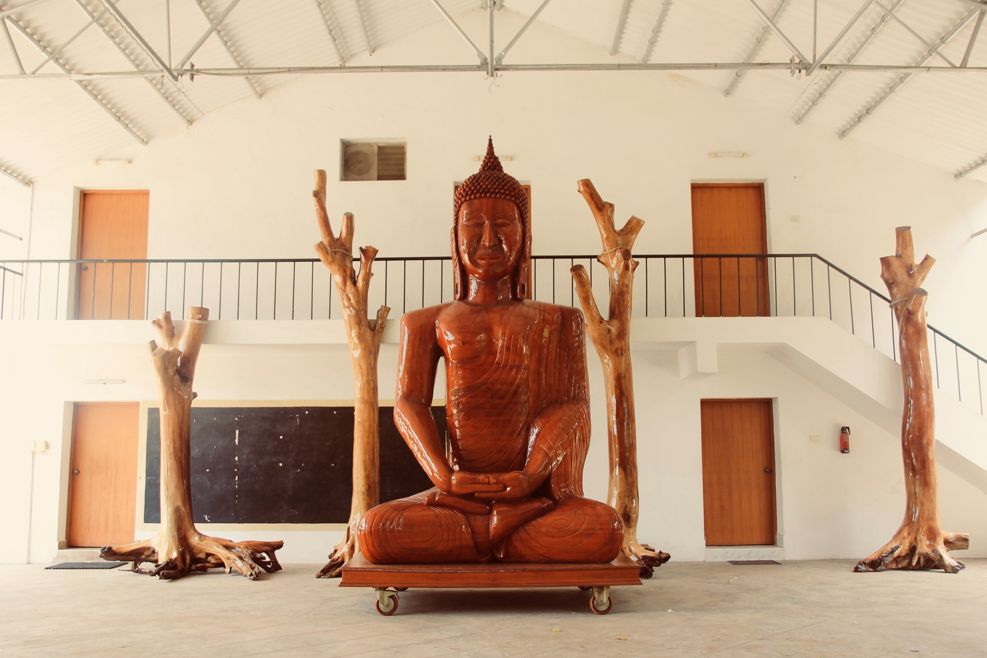 Wooden sculpture resting on a wheeled trolley base in the studio